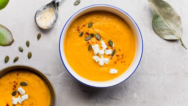 Lunchbox: Sch&uuml;ssel mit einer leuchtend orangen Suppe, mit K&uuml;rbiskernen darin.