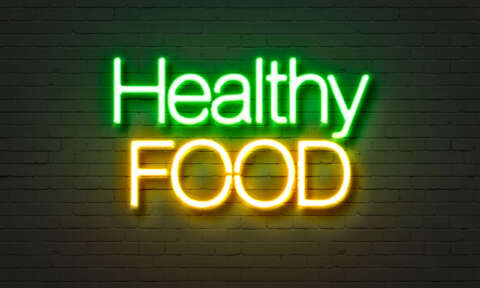 Clean Eating: Neonschild mit Aufschrift Healthy food auf einer Ziegelsteinwand