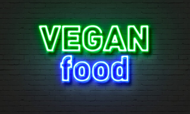 Vegan: Neonschild mit Aufschrift Vegan food auf einer Ziegelsteinwand