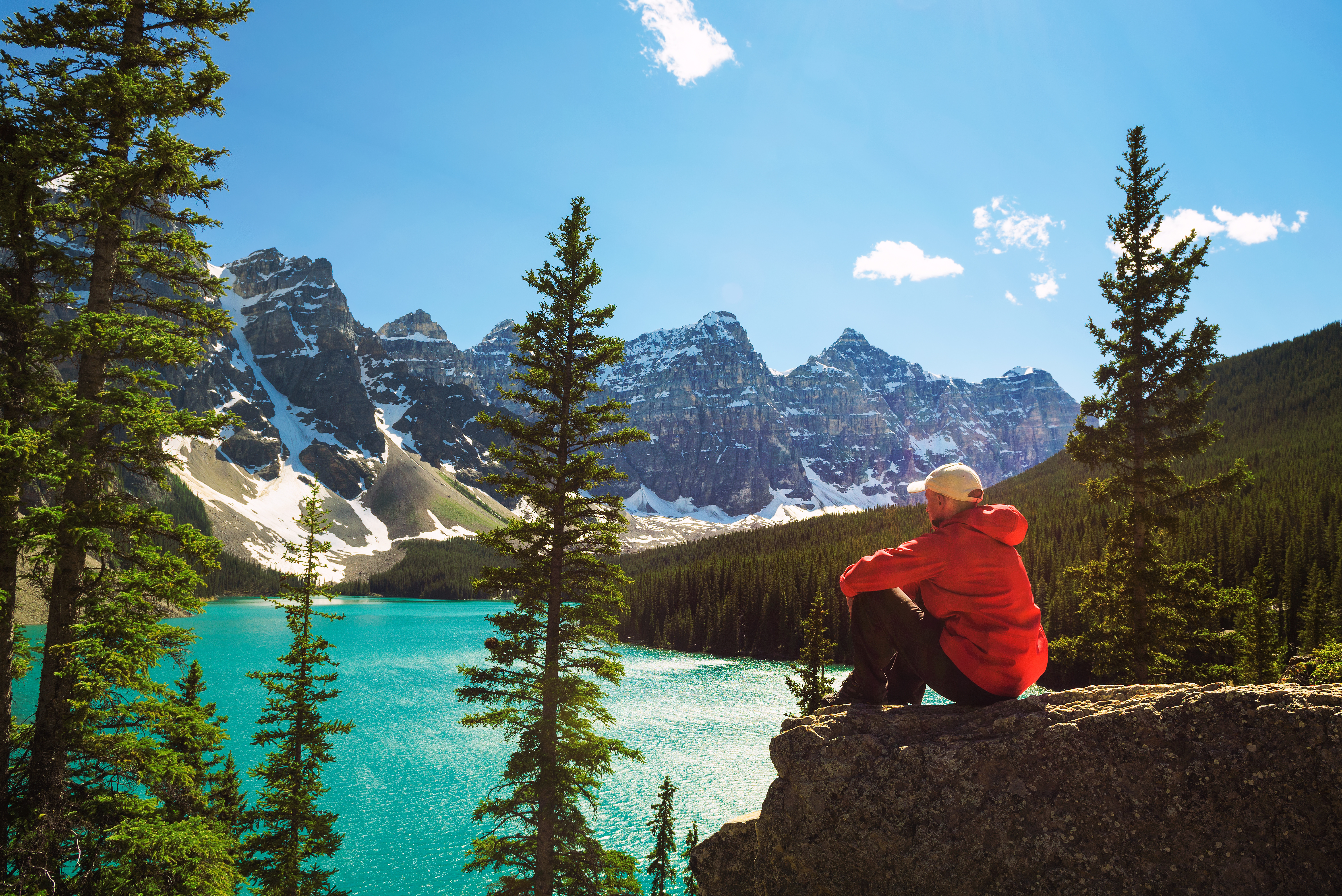 Mindfulness: In Mann in roter Jacke sitzt auf einem Stein und blickt auf den Morraine Lake
