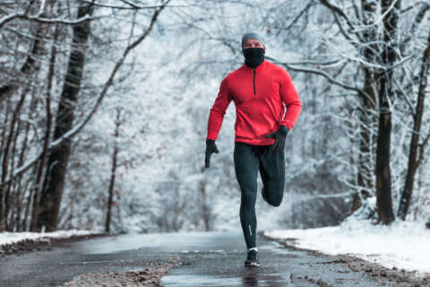 Laufen im Winter: Mann mit Mütze, Schal und Handshuh joggt durch Winterlandschaft