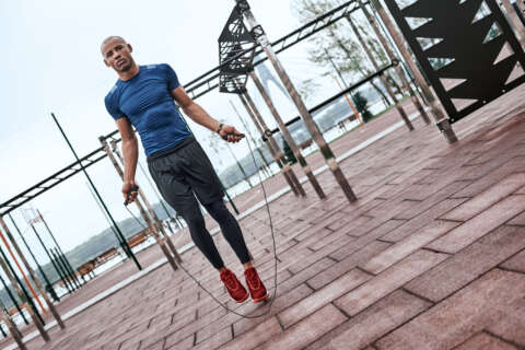 Seilspringen: Ein Mann springt draußen auf einem Trainingsparcours Seil