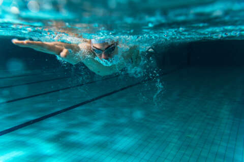 Unterwasseraufnahme von einem schwimmenden Mann im Schwimmbad.