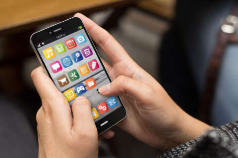 Gehirnjogging: Jemand hält ein Smartphone zwischen den Händen. und tippt auf die Apps auf dem Display