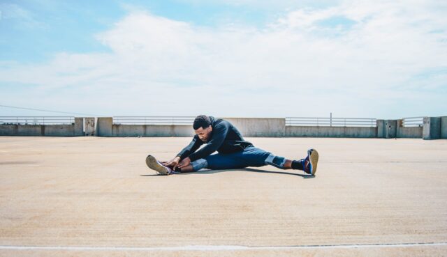 Outdoor-Sport: Mann stretcht sich im Sitzen auf einem Flachdach.
