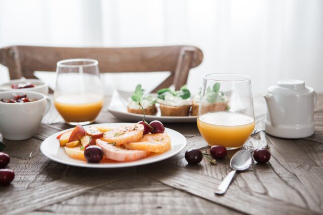 Hautpflege: Dazu gehört auch ausgewogene Ernährung. Obst, Saft und Quarkbrote stehen auf einem Holztisch