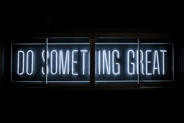 Neonschild mit Schriftzug Do Something Great hinter einem Fenster