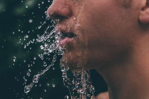 Wasser spritzt vom Gesicht eines Mannes weg