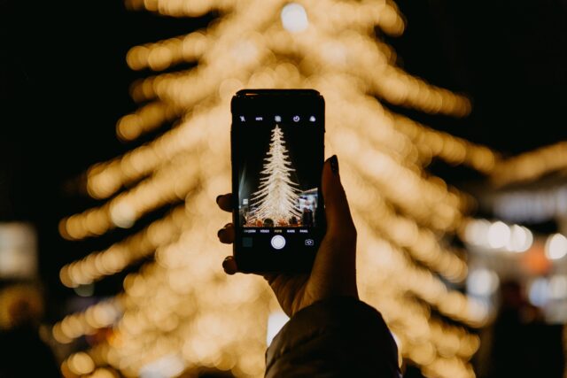 Jemand macht ein Foto von einem Weihnachtsbaum draußen