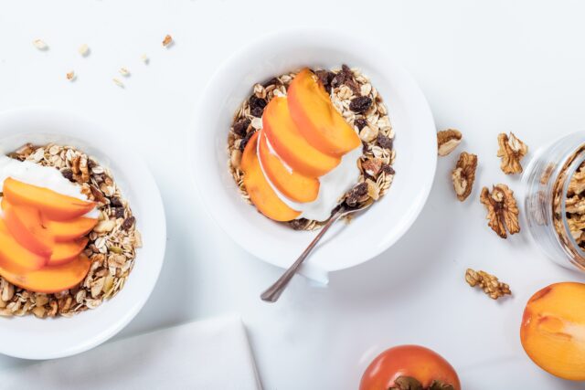 Lunchbox: Sch&uuml;sseln mit M&uuml;sli, Joghurt und aufgeschnittenem Obst auf wei&szlig;en Untergrund