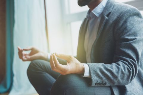 Manager gesund: Mann im Anzug meditiert im Lotussitz