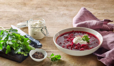 Typisch für die russische Küche: Teller mit Rote Beete-Suppe auf einem Holztisch