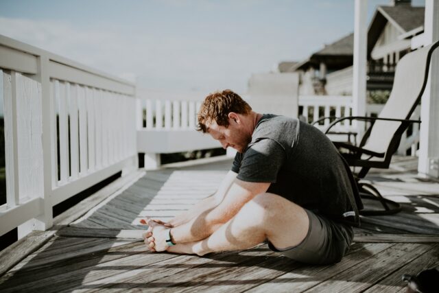Entspannung: Mann sitzt in Yoga-Pose auf der Veranda.
