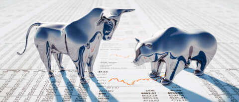 Aktien: Bulle und Bär stehen auf Zeitungsseite mit Aktienkursen