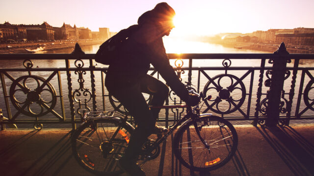 Radfahren: Mann f&auml;hrt mit Fahrrad &uuml;ber Br&uuml;cke