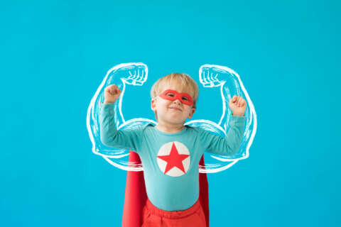 Superfoods: kleiner Junge, als Superheld verkleidet, mit geuzeichneten Armen und Muskeln eines Erwachsenen