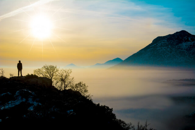 Mann betrachtet einen Sonnenuntergang in den Bergen