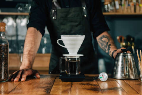 Filterkaffee: Ein Mann brüht Kaffee mit einem Filter auf, Daneben steht eine Kanne und liegt ein Thermometer.