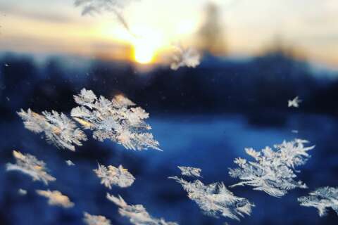 Winterblues: Fenster mit Eiskristallen vor eine verschwommenen Winterlandschaft