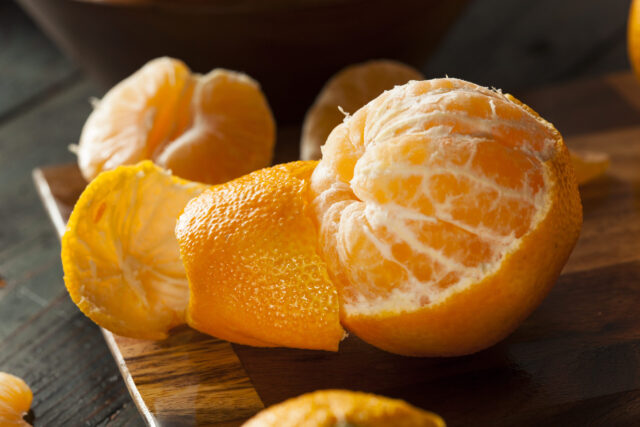 Zero-Waste: Mandarine auf einem Holzbrett, die zur Hälfte geschält ist