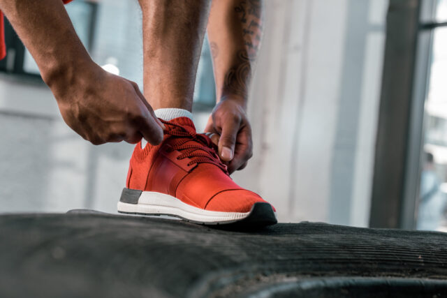Sportler schnürt rote Sportschuhe vor dem Training zu