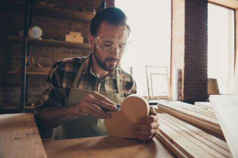 Herz in Form: Mann mit Bart arbeitet konzentriert an einem Holzherz