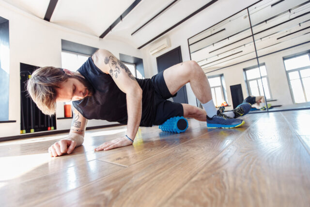 Faszientraining: Ein Mann trainiert seinen Oberschenkel auf einer Faszienrolle