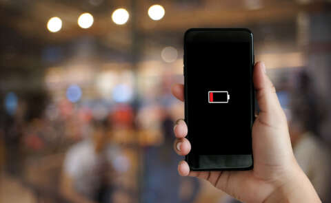 Blutdruck: Ein Mann hält ein Telefon in der Hand bei dem das Batteriesymbol rot erleuchtet ist.