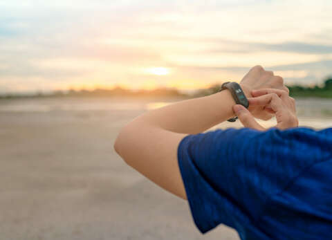 Bluthochdruck: Eine Frau steht am Strand und aktiviert ein Wearable