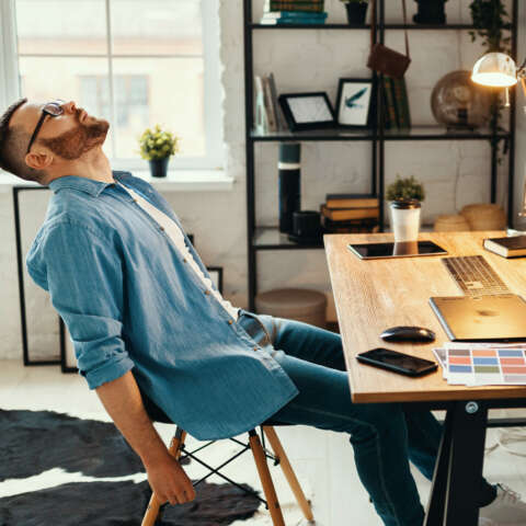 Endlich Frühling: Mann sitzt müde an einem Schreibtisch