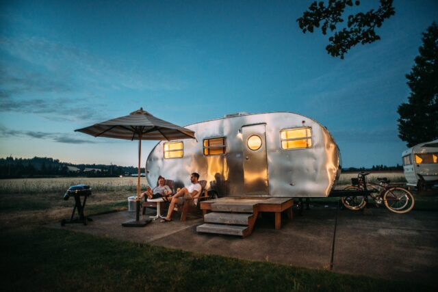 Outdoor-Typ: junges Paar sitzt bei Sonnenuntergang vor einem Campingwagen