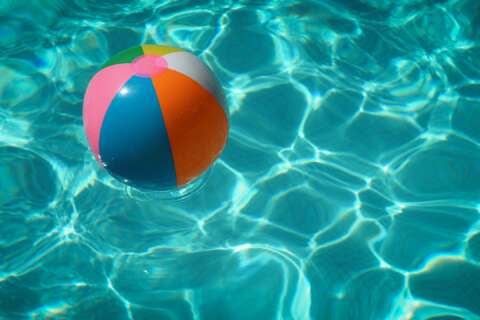 Endlich Sommer: Ein Beachball schwimmt in einem blauen Pool