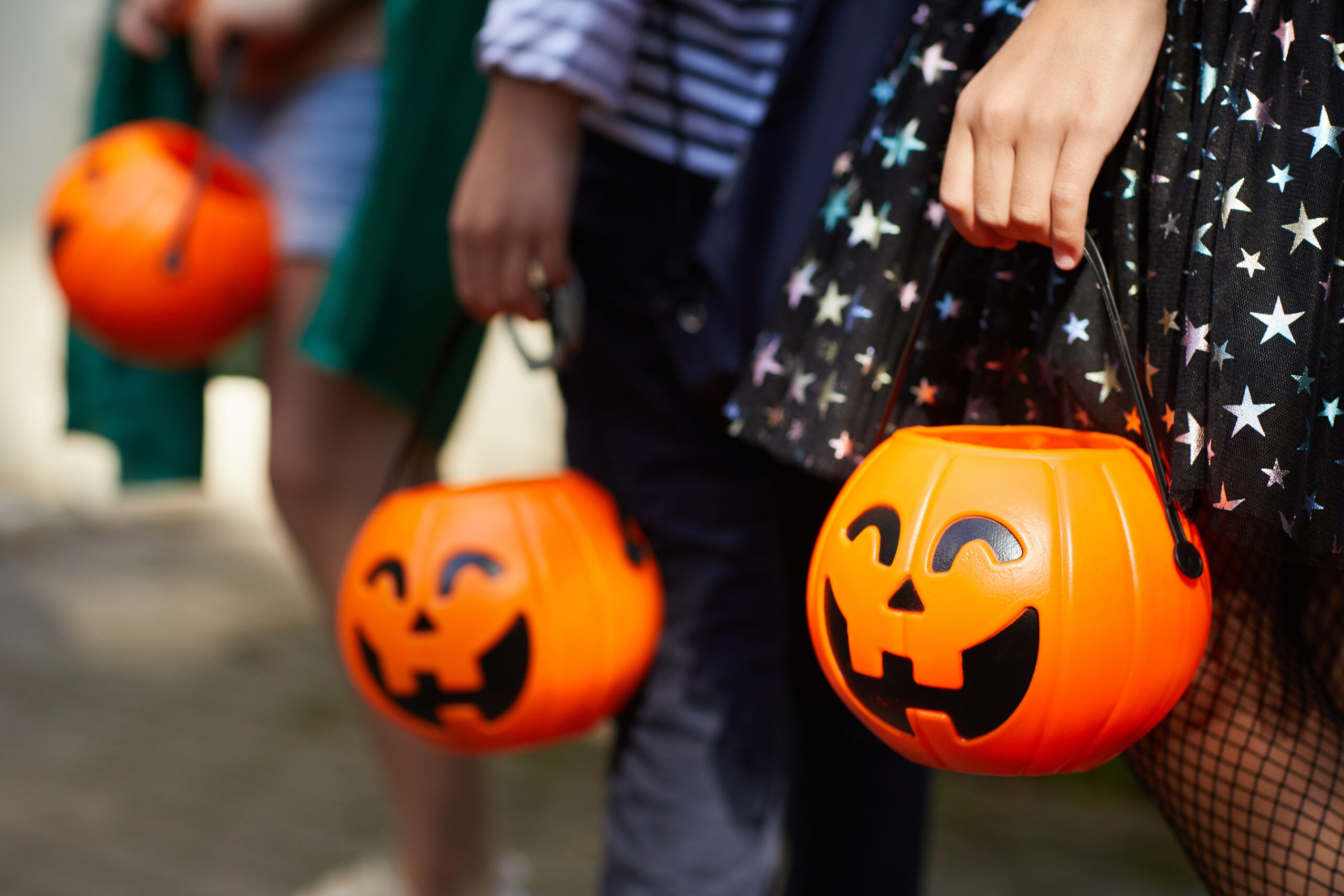 Halloween: Nahaufnahme von Kindern mit Kürbiseimer beim trick or treat