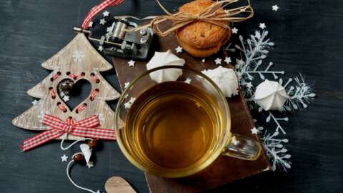 Gesündere Weihnachten: Glastasse mit Tee und weihnachtlichem Gebäck und Deko
