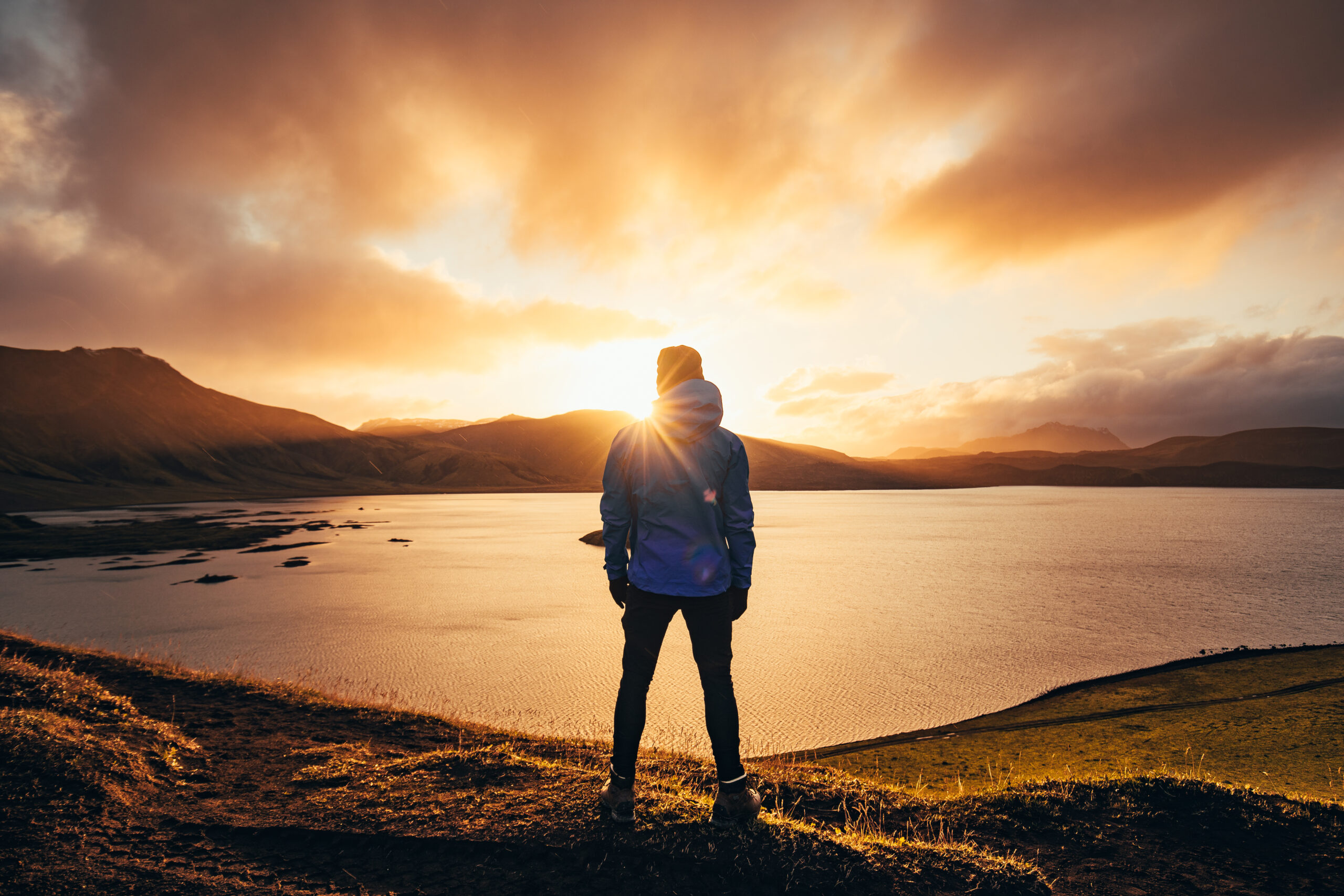 Vorsatz der sich lohnt: Mann in blauer Jacke schaut auf Sonnenuntergang.