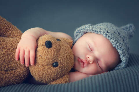 Einfach einschlafen: Baby mit Teddybär auf einer weichen Decke