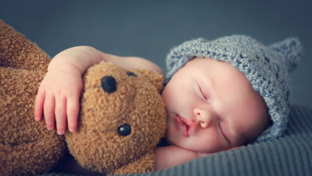 Einfach einschlafen: Baby mit Teddybär auf einer weichen Decke