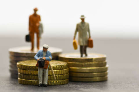 Aktienrente: kleine Figuren älterer Menschen sitzen auf gestapelten Euro-Münzen.