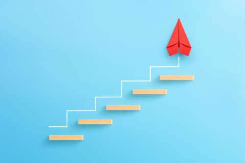 Mythen1: Wooden block stacking as step stair with red paper plane on blue background, Ladder of success in business growth concept, copy space