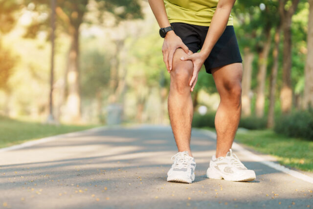 Mythen Gelenke Joggen: Junger Mann in kurzen Hosen h&auml;lt sich sein Knie