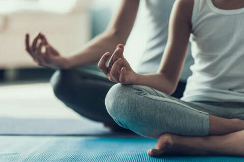 Atmen: Mädchen und Frau machen Yoga im Schneidersitz.