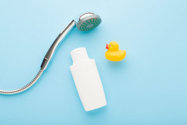 Wechseldusche: Blauer Hintergrund mit Duschkopf, Badeente und Shampooflasche.