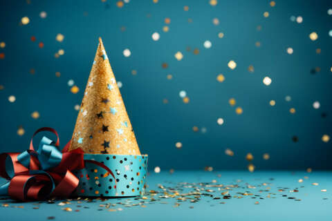 Neujahrsbräuche: Partyhut mit Glitzerkonfetti im Hintergrund.